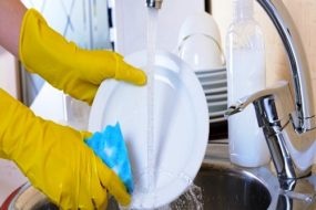 Close up hands of woman washing dishes in kitchen